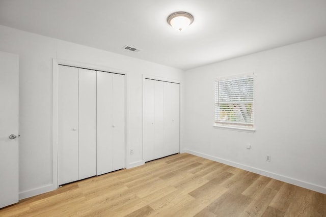 1317 Mckie Cv, Austin, TX 78752 - unfurnished bedroom featuring multiple closets, light wood-style floors, and baseboards