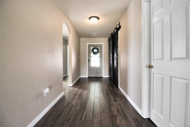 doorway featuring dark wood-style floors, arched walkways, and baseboards