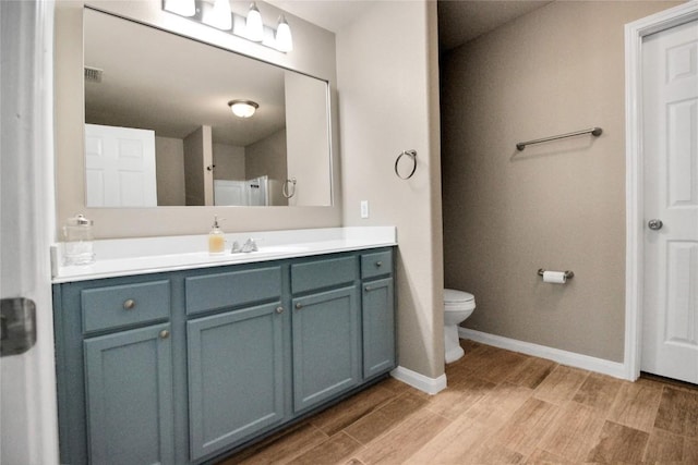 full bath featuring vanity, wood finished floors, toilet, baseboards, and a shower