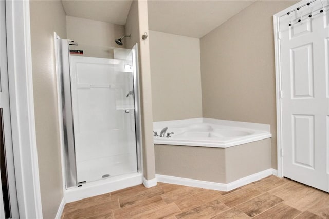 bathroom with a shower stall, wood finished floors, and a bath