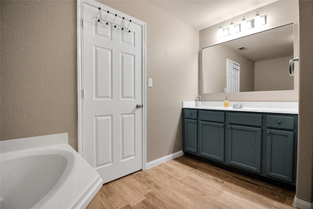 bathroom with wood finished floors, vanity, and a bath