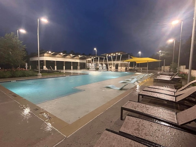 pool at twilight with a community pool and a patio