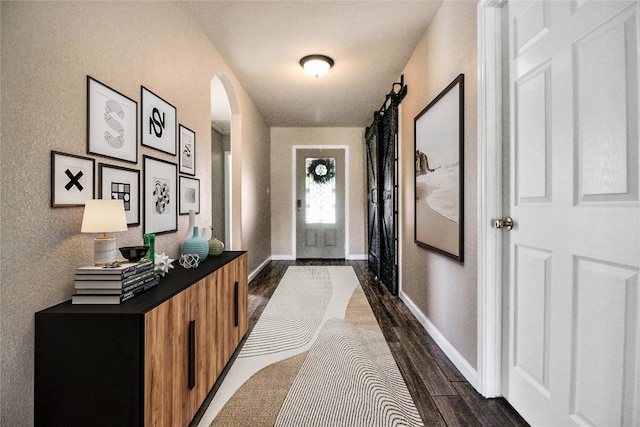 doorway to outside featuring dark wood finished floors, arched walkways, and baseboards