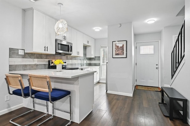 3820 Southway Dr Unit C, Austin, TX 78704 - kitchen with stainless steel appliances, a peninsula, a kitchen breakfast bar, light countertops, and white cabinets