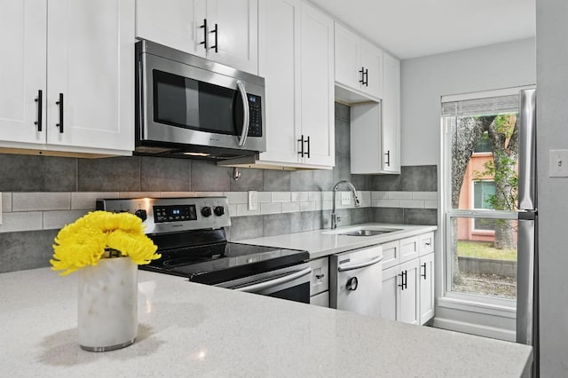 3820 Southway Dr Unit C, Austin, TX 78704 - kitchen featuring stainless steel appliances, a sink, white cabinets, decorative backsplash, and light stone counters