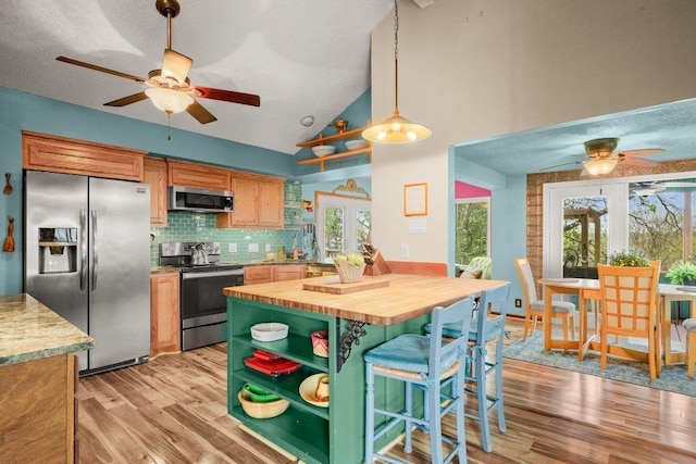 6906 Chinook Dr, Austin, TX 78736 - kitchen with appliances with stainless steel finishes, wooden counters, ceiling fan, light wood-style flooring, and vaulted ceiling