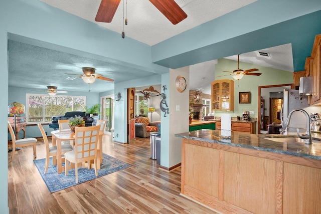 6906 Chinook Dr, Austin, TX 78736 - kitchen featuring a ceiling fan, a textured ceiling, a large fireplace, a peninsula, and light wood-type flooring