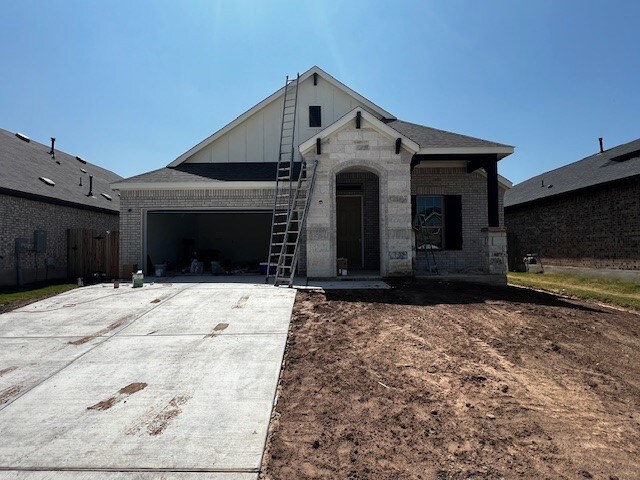 510 Durian Loop, Buda, TX 78610 - french country home with brick siding, board and batten siding, a garage, and concrete driveway