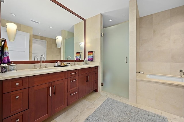 bathroom featuring tile patterned floors, a bath, a stall shower, and double vanity
