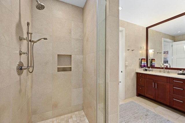 bathroom with a tile shower and vanity
