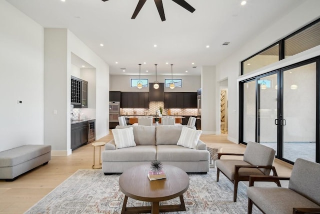 living room with light wood-type flooring, beverage cooler, a ceiling fan, and recessed lighting