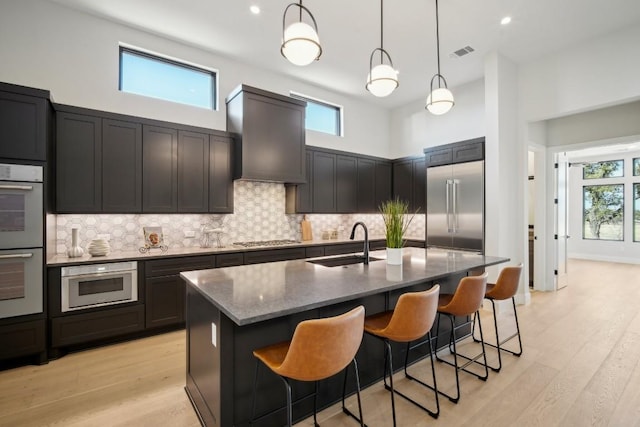 kitchen featuring a sink, stainless steel appliances, decorative backsplash, dark stone counters, and recessed lighting