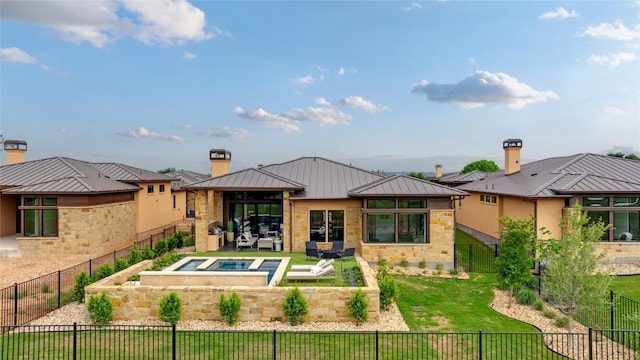 back of property featuring a standing seam roof, a chimney, an in-ground hot tub, metal roof, and a patio area