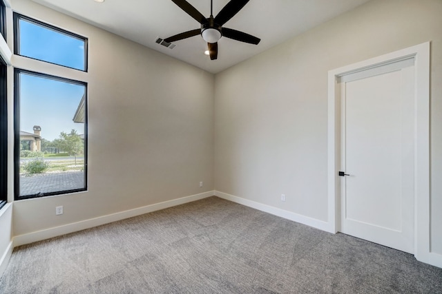 empty room featuring carpet, a ceiling fan, and baseboards