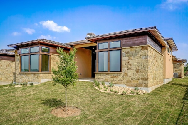 rear view of property featuring stone siding, a lawn, and central AC