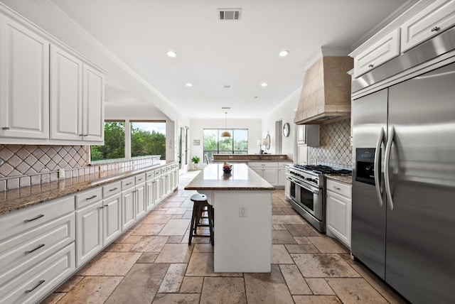 4020 Texas Wildlife Trl, Austin, TX 78735 - kitchen featuring stainless steel appliances, custom range hood, stone tile flooring, white cabinetry, and tasteful backsplash