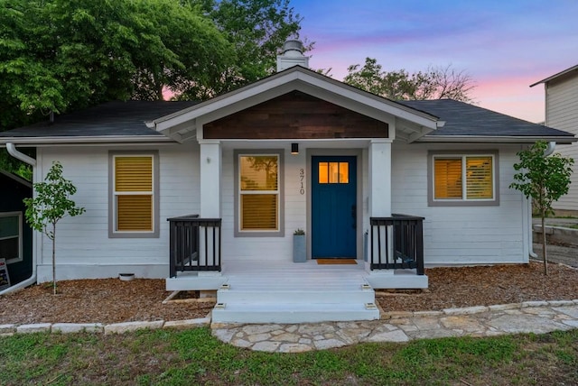 bungalow-style home featuring a chimney and a shingled roof