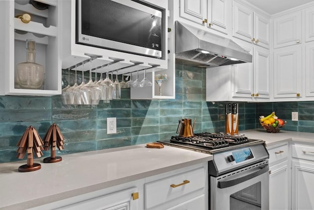 kitchen with appliances with stainless steel finishes, under cabinet range hood, light countertops, white cabinets, and backsplash