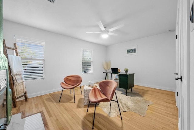 living area featuring wood finished floors, ceiling fan, and baseboards