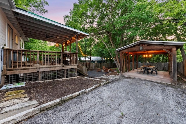 yard at dusk with a gazebo, a deck, a fenced backyard, and a patio area