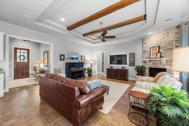 128 Tuscany Way, Georgetown, TX 78633 - living area featuring a tray ceiling, a ceiling fan, tile patterned flooring, a stone fireplace, and beam ceiling