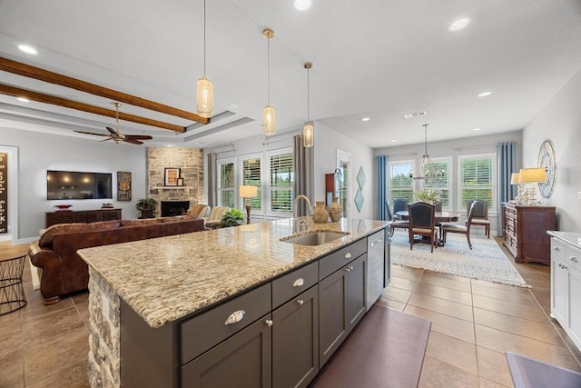 128 Tuscany Way, Georgetown, TX 78633 - kitchen featuring a sink, stainless steel dishwasher, a fireplace, light stone countertops, and a ceiling fan