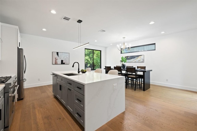 3705 Wilson St Unit 1, Austin, TX 78704 - kitchen featuring stainless steel appliances, gray cabinets, an island with sink, wood finished floors, and light countertops