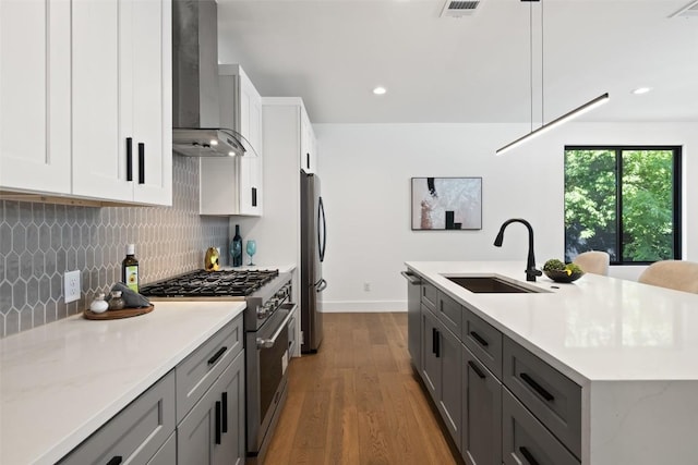 3705 Wilson St Unit 1, Austin, TX 78704 - kitchen featuring wall chimney exhaust hood, stainless steel appliances, dark wood-style floors, tasteful backsplash, and a kitchen island with sink