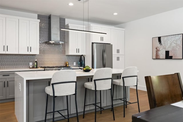 3705 Wilson St Unit 1, Austin, TX 78704 - kitchen featuring wall chimney exhaust hood, freestanding refrigerator, a kitchen island with sink, light countertops, and backsplash