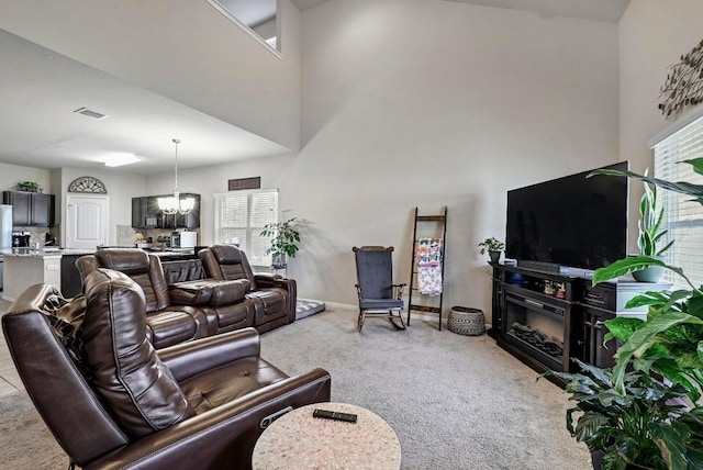 living room with light colored carpet, a chandelier, healthy amount of natural light, a towering ceiling, and baseboards