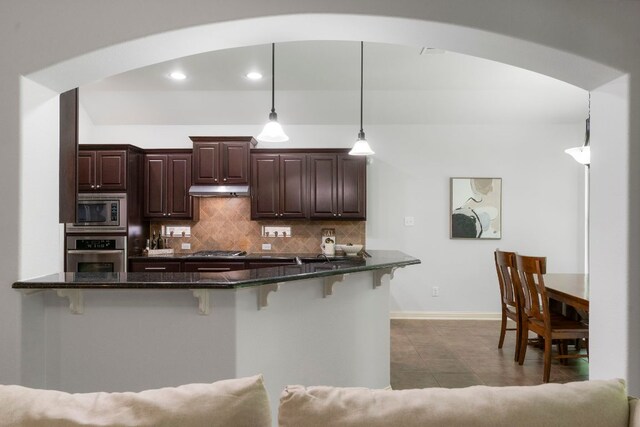 630 Wild Rose Dr, Austin, TX 78737 - kitchen featuring appliances with stainless steel finishes, arched walkways, a breakfast bar area, backsplash, and dark brown cabinets