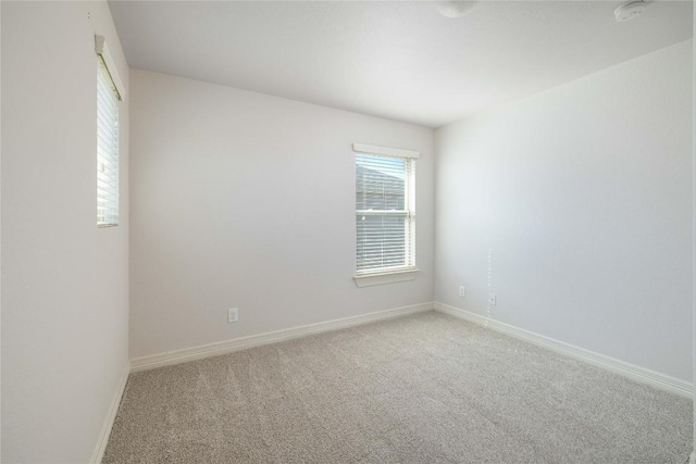 unfurnished room featuring light carpet, a smoke detector, and baseboards