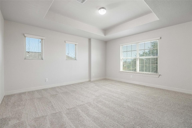 carpeted empty room with a tray ceiling and baseboards
