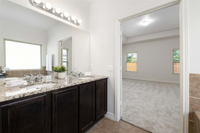 bathroom with double vanity, baseboards, and tile patterned flooring