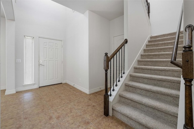 foyer with light tile patterned floors, stairway, and baseboards