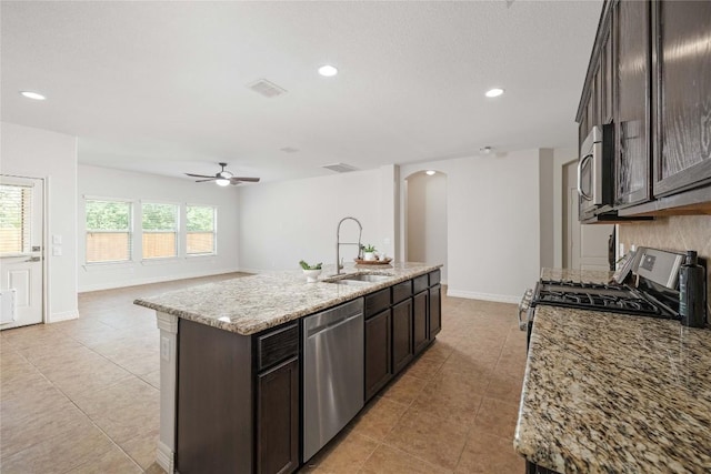 kitchen featuring a sink, stainless steel appliances, arched walkways, light tile patterned floors, and ceiling fan