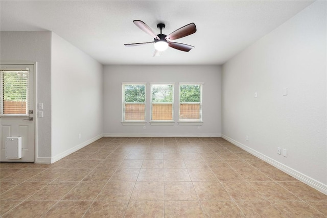 spare room featuring a ceiling fan, light tile patterned flooring, and baseboards