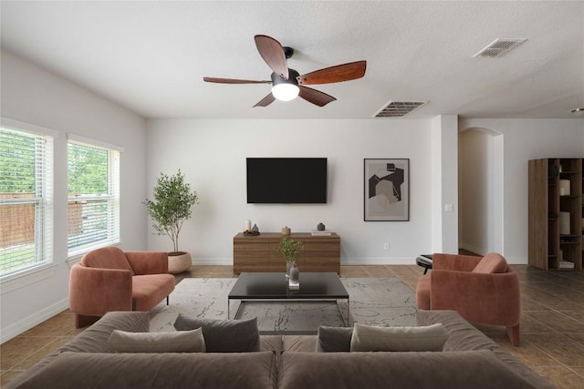 living area featuring a ceiling fan, baseboards, light tile patterned floors, and arched walkways