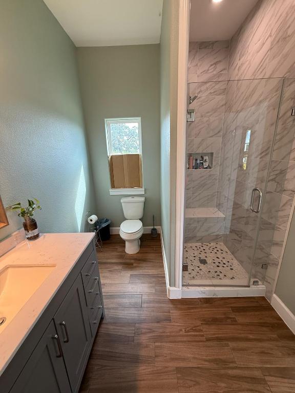 497 Brown Rd, Mcdade, TX 78650 - bathroom featuring baseboards, toilet, a stall shower, vanity, and wood finished floors
