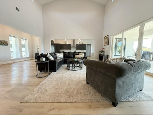 living area featuring high vaulted ceiling, light wood-style floors, and baseboards