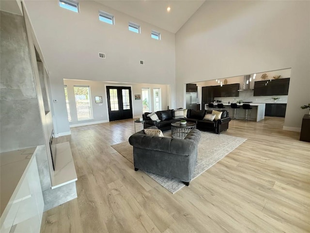living area featuring light wood finished floors, high vaulted ceiling, baseboards, and recessed lighting