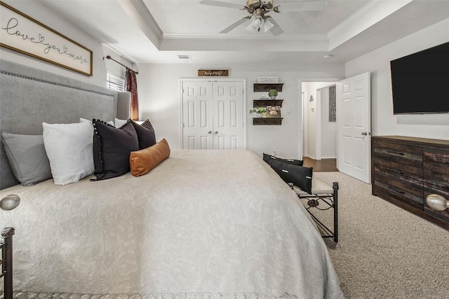 bedroom with a raised ceiling, crown molding, carpet flooring, a closet, and a ceiling fan