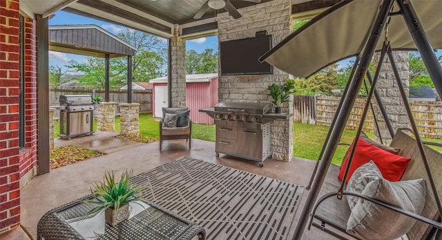 view of patio / terrace with area for grilling, a ceiling fan, a fenced backyard, and an outbuilding