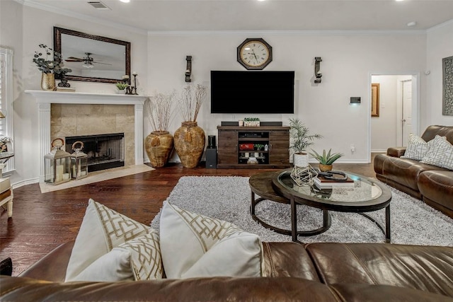 living room with wood finished floors, a tile fireplace, crown molding, baseboards, and recessed lighting