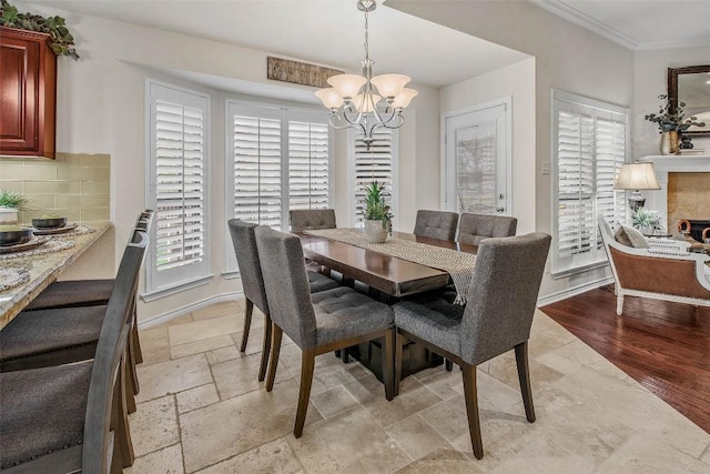 dining space featuring healthy amount of natural light, a chandelier, crown molding, and stone tile flooring