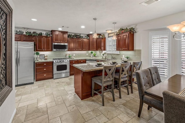 kitchen featuring stainless steel appliances, plenty of natural light, a peninsula, stone tile flooring, and recessed lighting
