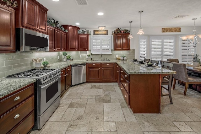 kitchen with stainless steel appliances, stone tile flooring, a sink, a breakfast bar area, and a peninsula
