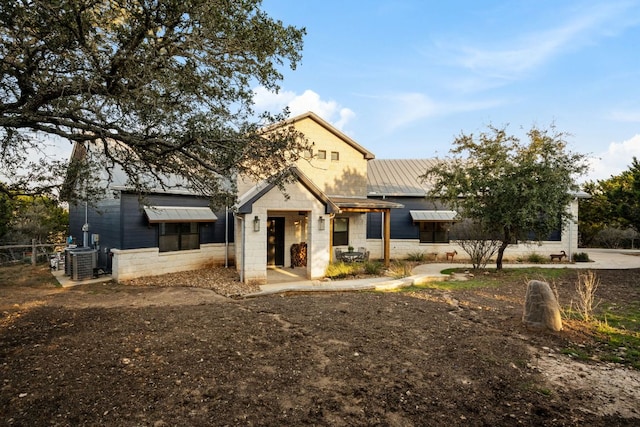 124 Hoskins Trl, Boerne, TX 78006 - view of front facade with central air condition unit, a standing seam roof, stone siding, and metal roof