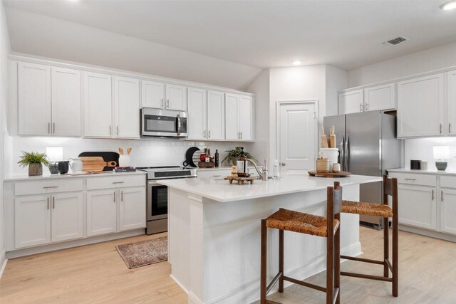 552 Tekoa Dr, Georgetown, TX 78628 - kitchen with appliances with stainless steel finishes, backsplash, light wood-style flooring, a breakfast bar, and recessed lighting
