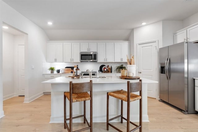 552 Tekoa Dr, Georgetown, TX 78628 - kitchen with appliances with stainless steel finishes, tasteful backsplash, light wood-style flooring, a breakfast bar area, and lofted ceiling